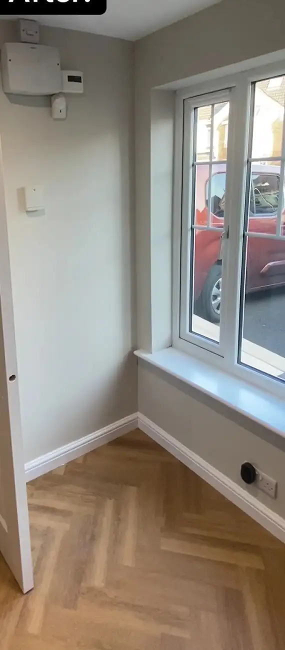 Newly decorated room with grey walls, white door and skirting and herringbone floor