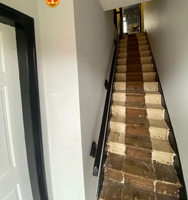 Hallway and staircase painted in pale grey with black skirting and handrail