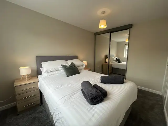 Bedroom decorated in warm grey with white woodwork and mirrored wardrobe
