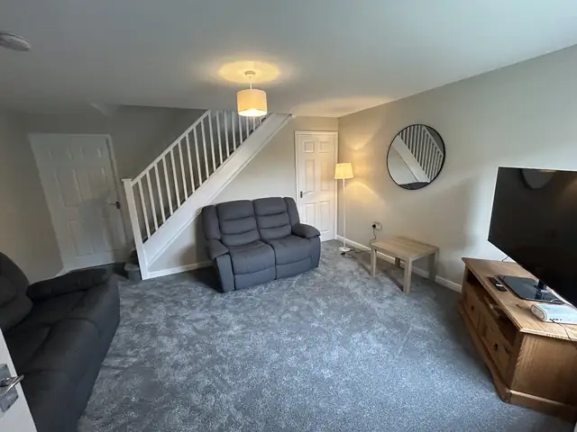 Freshly decorated lounge with grey walls, white staircase and grey carpet
